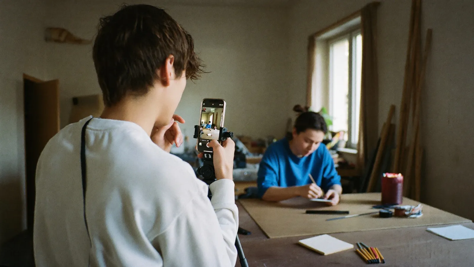 Junger Handwerker filmt mit dem Smartphone einen Kollegen bei der Arbeit für Social-Media-Content